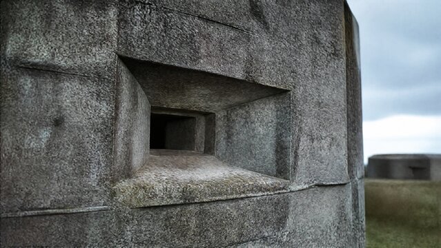 Close-up of a grey concrete blockhouse, square firing port and rough textured surface.