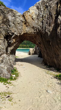Natural arch in a massive rock overlooking the beach.