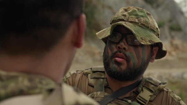 Two soldiers in camouflage are intensely strategizing during a tactical briefing for a covert military operation in a rugged outdoor environment.