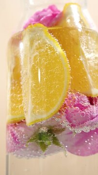 Close-up of air bubbles on a lemon and roses in refreshing drinking water