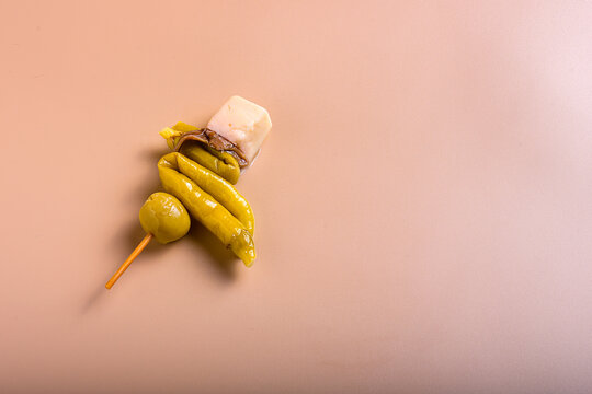 Traditional basque gilda tapas with green olives anchovies piparra peppers and cheese cubes with copy space on beige background