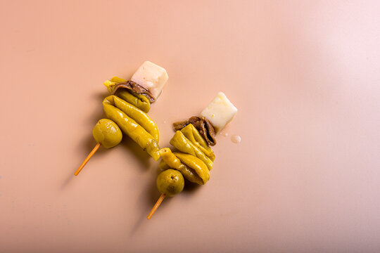 Traditional basque gilda tapas with green olives anchovies piparra peppers and cheese cubes with copy space on beige background