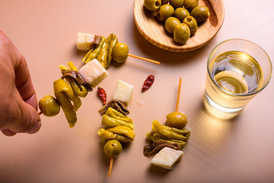 Traditional basque gilda tapas with green olives anchovies piparra peppers and cheese cubes with copy space on beige background