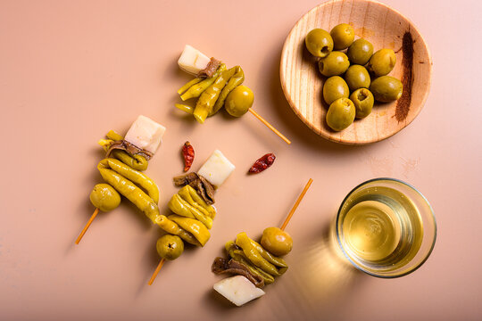 Traditional basque gilda tapas with green olives anchovies piparra peppers and cheese cubes with copy space on beige background