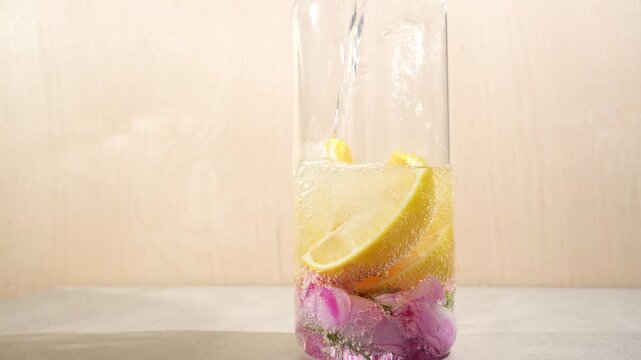 Water is poured into a jug to make refreshing water with lemon and rose