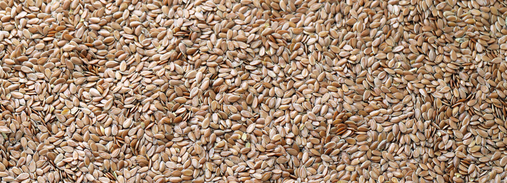 Brown flax seeds in big pile on table close up. Large amount of flax seeds