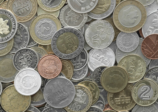 Top view of assorted coins, numerous world currencies together. Shiny metal pieces in mound