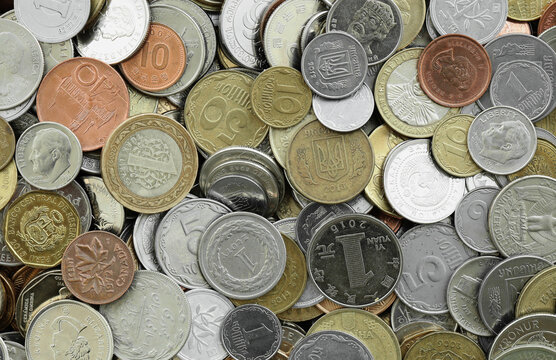 Top view of assorted coins, numerous world currencies together. Shiny metal pieces in mound