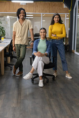 Fototapeta premium Diverse coworkers posing in modern open-plan office, seated woman center with swivel chair
