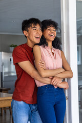 Naklejka premium Vertical video: Partner wrapping arms, couple laughing at kitchen door near fridge in red and pink