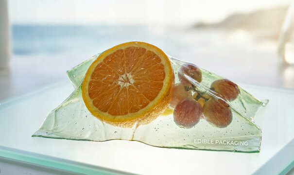 Edible packaging concept for fresh fruit with orange slice and grapes inside transparent eco friendly wrapper showing healthy food and sustainability.