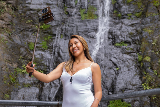 A Bolivian Latina woman taking a selfie at a waterfall in the town of Coroico in the Yungas region of Bolivia - the concept of nature