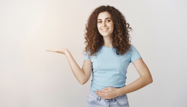 Smiling woman with curly hair gesturing to the side in casual attire