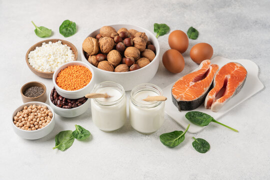 High protein food set with fresh salmon, eggs, cottage cheese, yogurt, lentils, chickpeas, beans and nuts arranged on white background with copy space. Healthy wellness nutrition concept 