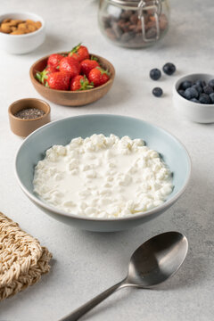 Fresh ingredients for a high protein cottage cheese bowl including blueberries, strawberries, chia seeds and almonds arranged on a light background with copy space