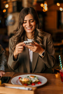 Woman photographing food with smartphone for social media sharing