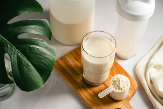 Protein shake with whey powder scoop on wooden board, healthy fitness nutrition