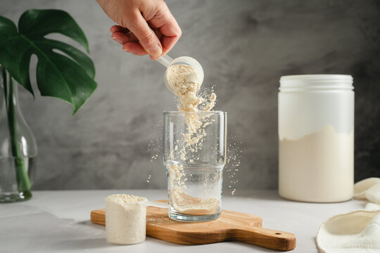 Protein powder being poured into glass, sports nutrition concept
