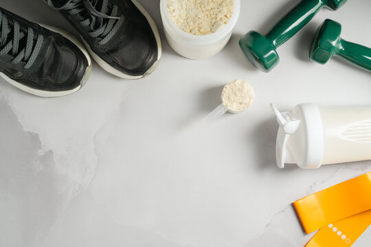 Fitness nutrition flat lay with protein shake, whey powder and workout equipment