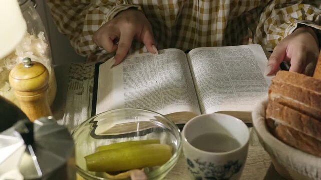 young conservative asian Woman Reading the Bible at table with bread food and drink indoors