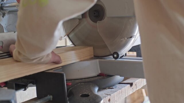 Carpenter cutting timber with a saw