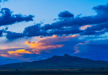Obraz premium Blue hour photography includes sunset scenes with Heart Mountain near Cody, Wyoming, USA.. Rolling clouds show orange glow with deep blue beauty.