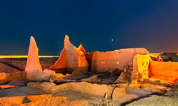 The illuminated mud brick ruins of At-Turaif World Heritage Site in historic Diriyah, Saudi Arabia, captured under a twilight sky.