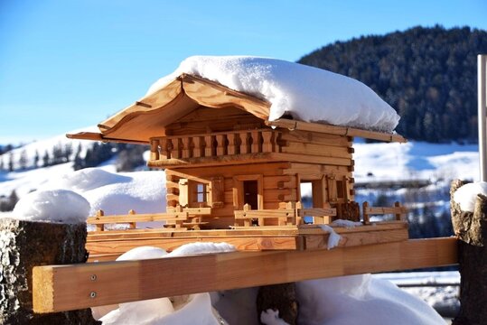 Beautiful wooden birdhouse shaped like a traditional alpine chalet covered with snow in Fiss, Austria