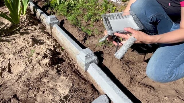 Painting concrete grave border with roller and brush during cemetery restoration