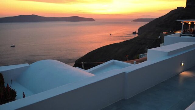 Golden sunset light reflecting on the Aegean Sea and caldera cliffs with whitewashed architecture in Fira, Santorini.