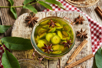 Naklejka premium Preparation of homemade nut liqueur or tincture from green unripe walnuts and spices