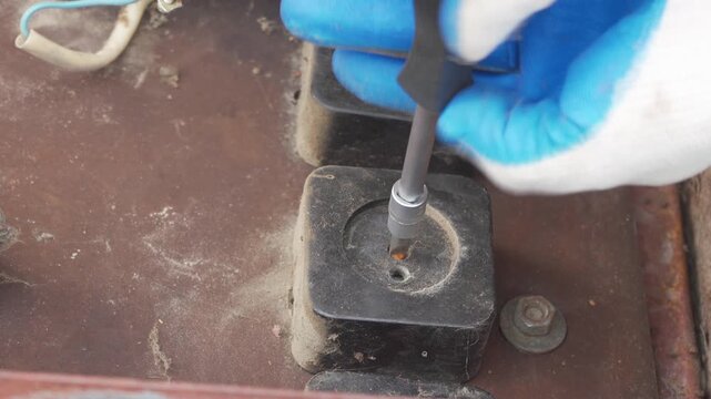 Repairing an old dusty electrical outlet with a screwdrive, Handyman unscrewing a black power outlet with a screwdriver