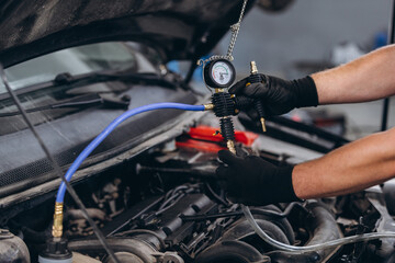 Fototapeta premium Mechanic checking car engine pressure using diagnostic tool