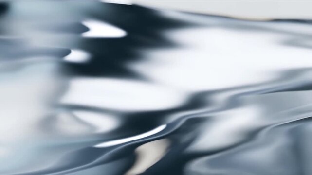 Slow motion closeup tracking pan of rippling metallic surface reflecting light on glossy liquid plane in minimal studio interior