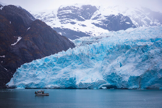 small boat in front of large glacier in kenai fjords national park