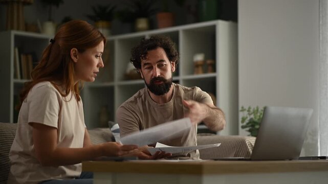 Stressed couple arguing over bills and finances at home. Frustrated man and woman discussing debt and budget problems