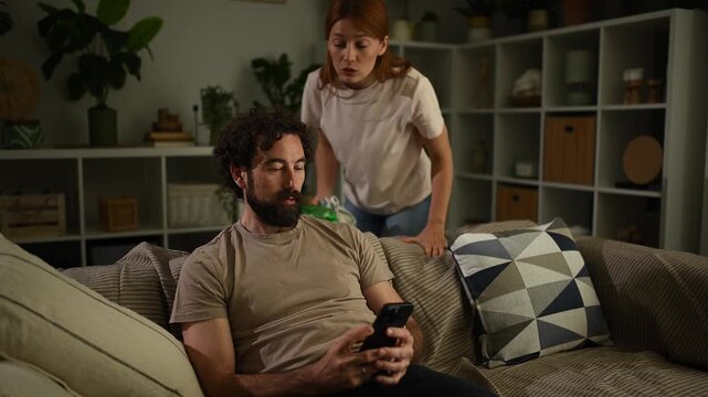 Jealous wife arguing with husband over his smartphone at home, relationship problems and distrust