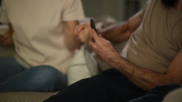 Woman trying to get husband's attention while he ignores her scrolling on his smartphone at home, relationship problems