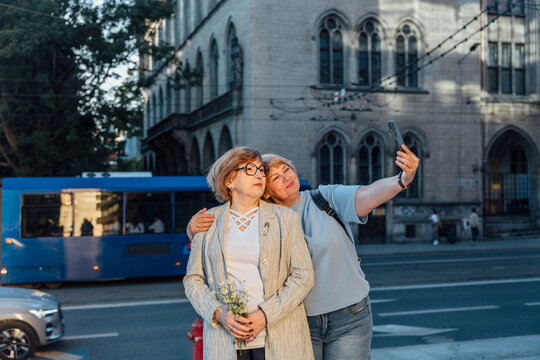 Happy Senior Women Taking Selfie Together on Historic City Street During Evening Walk
