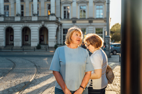 Thoughtful Senior Woman Standing Near Historic Theater Building During Golden Hour City Walk