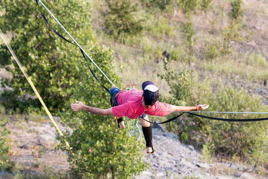 Man Balancing on Highline Slackline with Arms Outstretched Above Rocky Valley