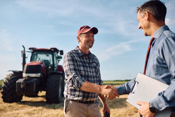Happy farmer owner greeting insurance agent in field. © Drazen