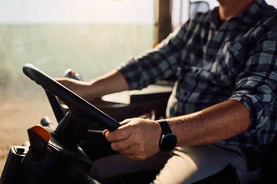 Close up farmer driving tractor in agricultural field.