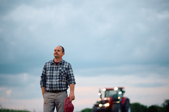 Mature agronomist in field against the sky.