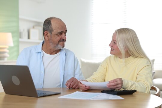 Pension. Senior couple with paperwork, laptop and calculator at table indoors