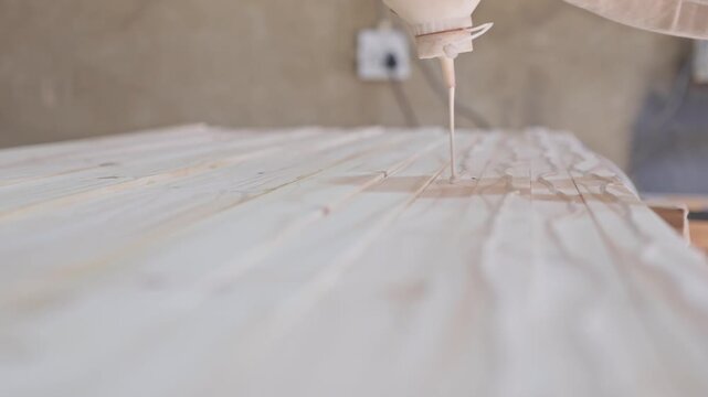 Carpenter applying glue to pine planks