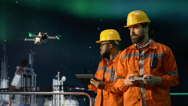 Drilling ship specialists using aerial reconnaissance gadget to circumvent maritime embargo, Offshore platform technicians working together, using drones to find fossil reserves during oil crisis.
