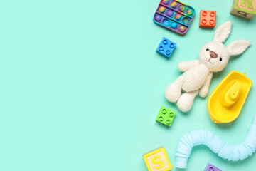 Childrens playtime essentials: knitted bunny, pop it fidget toy, building blocks, and sensory tube on mint background © Pixel-Shot