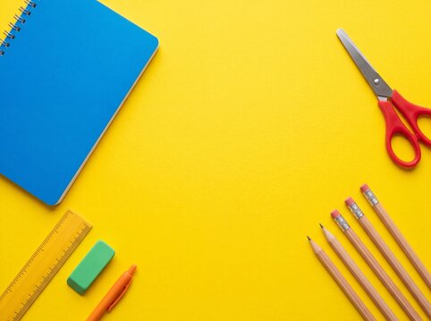 School and office supplies flat lay on yellow background with central copy space