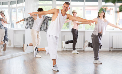 Fototapeta premium Dance group in casual clothes training to dance hip-hop and breakdance together in a dance center